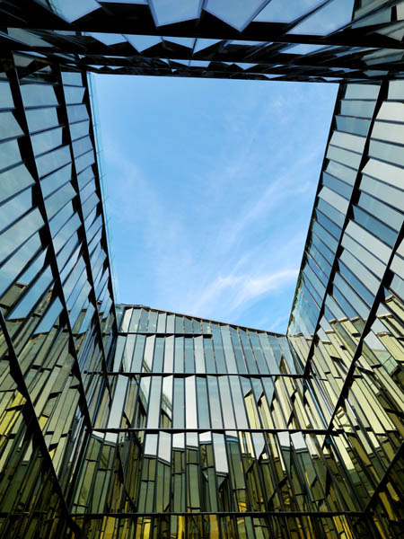 mage of 4 side glass facade reflecting different colors and the sky above