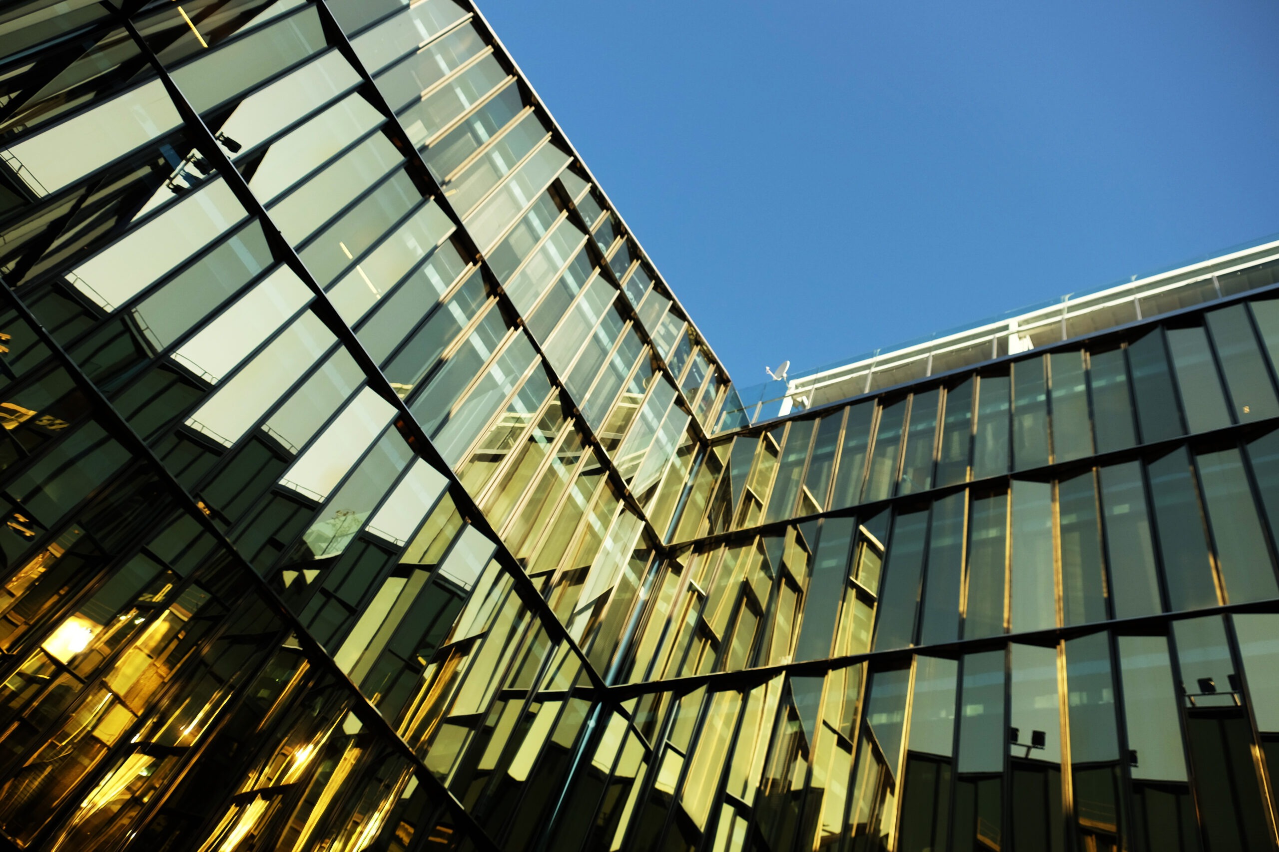full-field image of a glass facade reflecting different colors and sky above